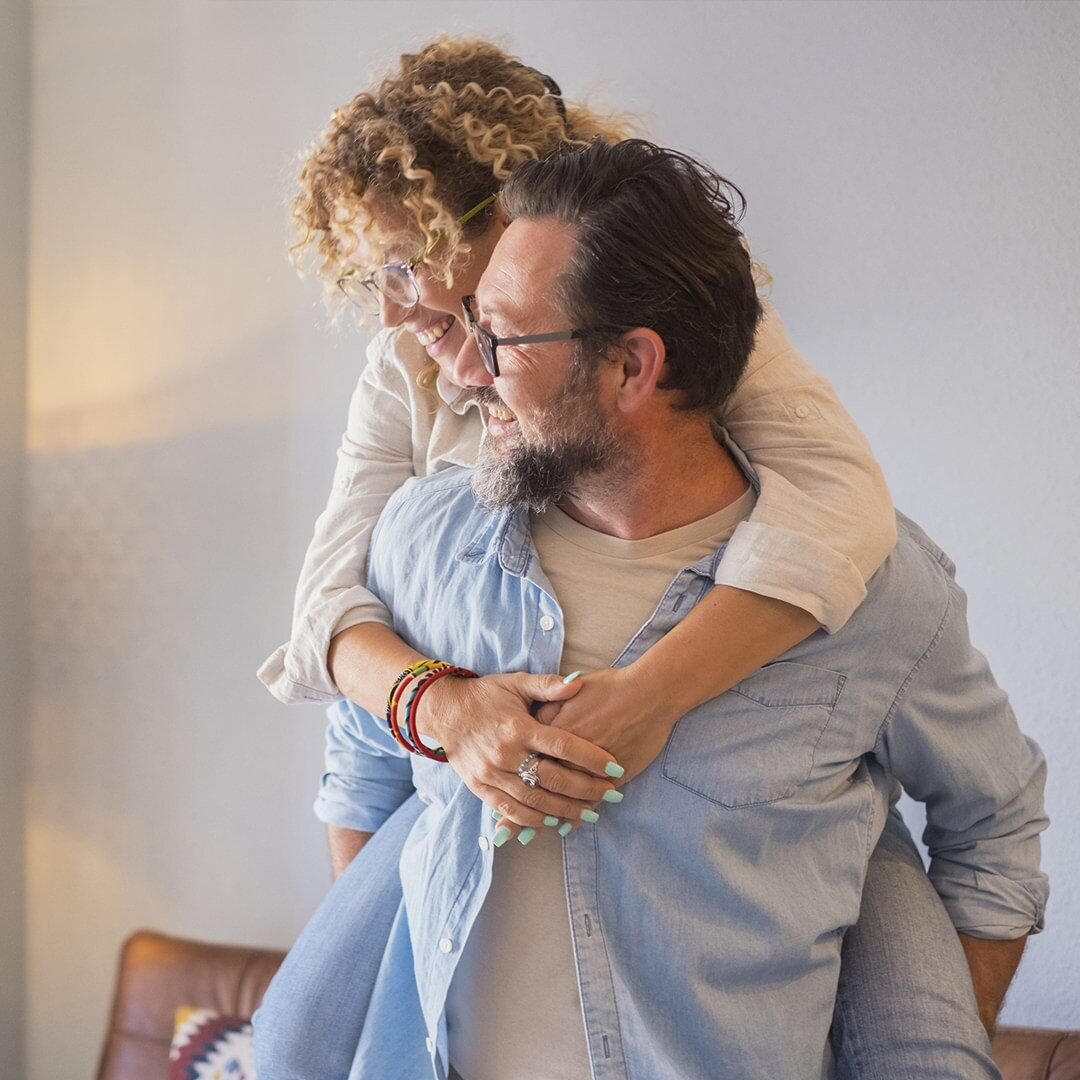 middle age couple happy man woman piggyback have fun enjoy together home smiling